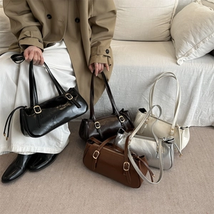 Retro PU leather underarm bags in five colors displayed by a model on a sofa