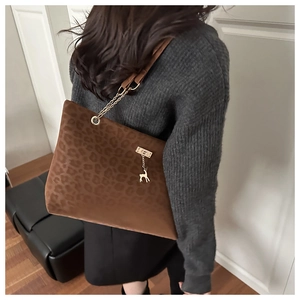 Close-up of brown leopard print tote bag with golden deer pendant and chain strap