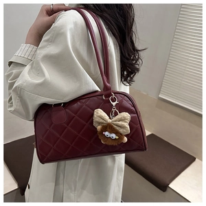 Close-up of wine red quilted shoulder bag with a cute plush monster charm detail