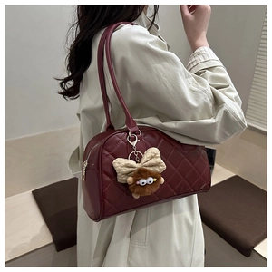 Detail view of burgundy quilted leather tote bag with cute plush bear and bow charms