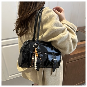Dettaglio della borsa Boston nera lucida con tasche anteriori e ciondolo di perline