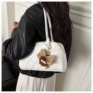 Detail of white quilted handbag featuring a brown plush bow charm with cute cartoon eyes