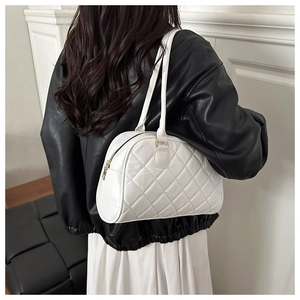 Detail of a white quilted tote bag with golden zipper on a model in black leather jacket
