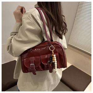 Detail of burgundy patent leather bag with buckles and colorful bead charms