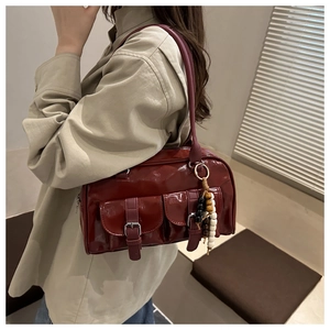 Dettaglio della borsa Boston vintage bordeaux con tasche con fibbia e ciondolo in legno