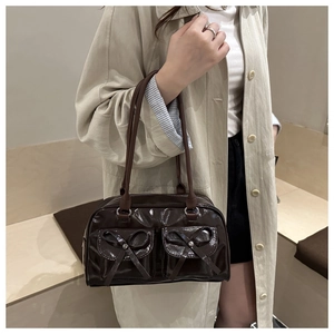 Detail of dark brown glossy patent leather bowling bag with cute bow pocket accents