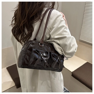 Detail of dark brown glossy bowling bag featuring bow accents and twin shoulder straps