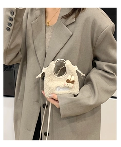 Detailansicht der cremefarbenen Plüschtasche mit Hasenpuppe und Cutie Bestickung als Tasche