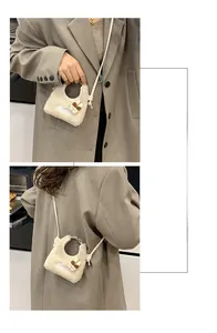 Mini Plüschtasche in Beige mit Hasen-Anhänger und Coffee-Stickerei am grauen Blazer