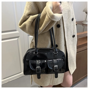Dettaglio della borsa Boston nera lucida con due tasche frontali e fibbie in metallo argentato