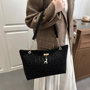 Borsa tote leopardata con catena dorata e ciondolo a cervo indossata da modella
