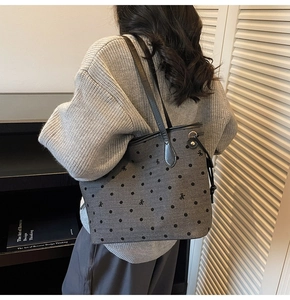 Close-up of gray polka dot tote bag featuring a black bow and premium leather trim