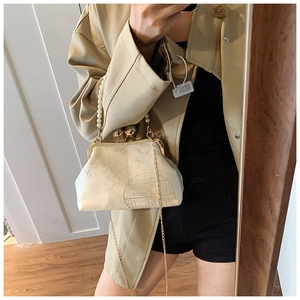 Detail of cream-colored kiss-lock bag featuring bamboo patterns and pearl handle