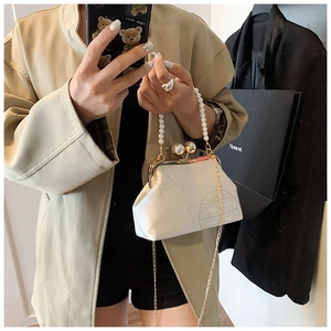 Detail of white vintage frame bag with pearl handle and geometric textured pattern