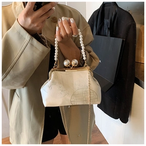 Detail of cream silk clutch with bamboo print, pearl handle, and gold frame clasp