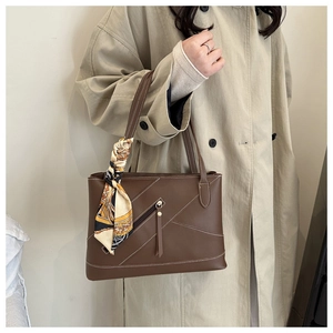 Detail of brown leather tote bag featuring white contrast stitching and silk scarf wrap