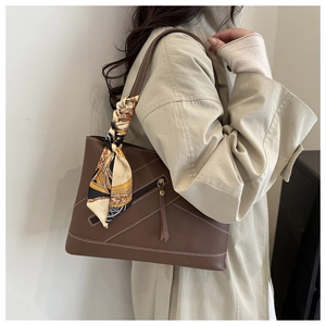 Detail of dark brown leather tote with contrast stitching and floral scarf handle