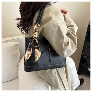 Detail van zwarte lederen shopper met witte stiksels en decoratieve zijden sjaal
