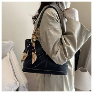 Close-up of black litchi pattern tote bag with white stitching and decorative silk scarf