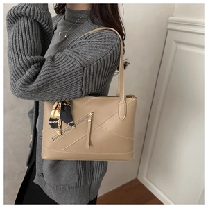 Detail van kaki kunstleren shopper met diagonale stiksels en decoratieve sjaal aan handvat