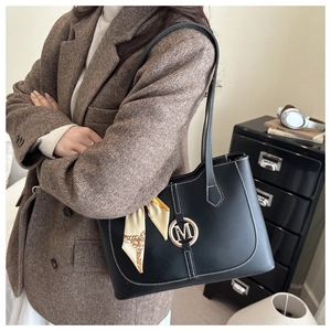 Detail der schwarzen Shopper-Tasche mit M-Logo, Kontrastnähten und dekorativem Seidenschal