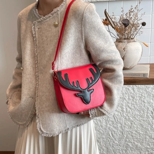 Red Christmas deer crossbody bag with black antlers shown on a model in a cozy setting