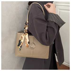 Detail der beige Tragetasche mit M-Metallschnalle und elegantem bedrucktem Seidentuch