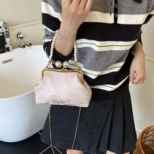 Pink jacquard evening bag with pearl handle and golden chain strap in a lifestyle setting