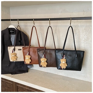 Row of large faux leather tote bags in four colors with cute plush bear pendants