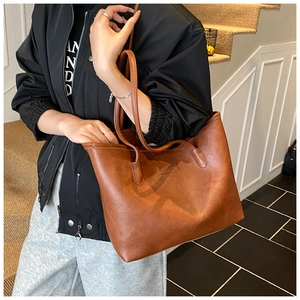 Macro shot of brown retro faux leather tote bag with embossed fashion logo and matte texture