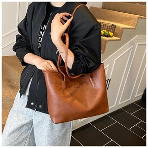 Detail of brown textured faux leather tote bag with Fashion label carried on shoulder