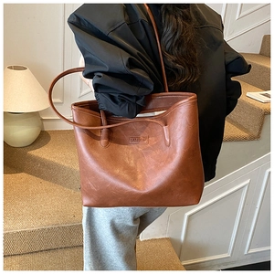 Detailed view of brown PU leather tote bag with FASHION logo worn by a model