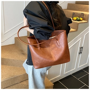 Detail of a large caramel brown tote bag featuring embossed FASHION logo on faux leather