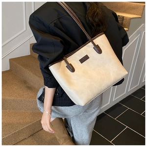 Detail of minimalist cream tote bag with brown straps and FASHION label on model