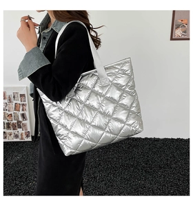 Gros plan d'un sac cabas argenté matelassé avec de larges bandoulières au style moderne épuré