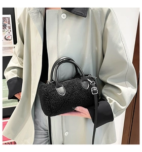 Detail of plush black cylindrical pillow bag with leather handles and silver hardware