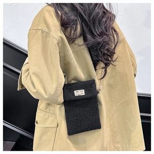 Detail of black teddy plush crossbody bag with gold chain strap and turn-lock on model