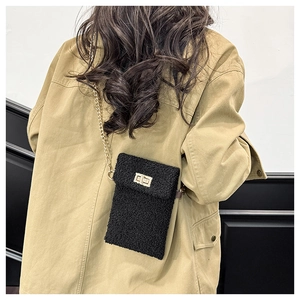 Detail of black faux fur plush crossbody bag featuring gold chain and turn-lock closure