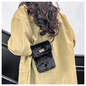 Detail of black faux fur mini crossbody bag with gold chain strap on model