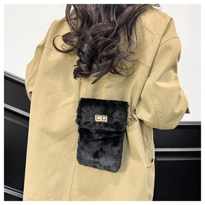 Detail of a black plush crossbody bag with a gold metal twist lock and chain strap