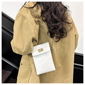 Close-up of white plush crossbody bag with gold twist lock and chain strap on model