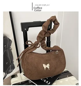 Détail du sac demi-lune café avec breloque papillon et bandoulière à nœud plissé