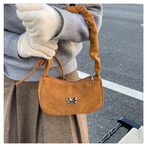 Detailed view of brown faux suede shoulder bag with silver butterfly and pleated strap