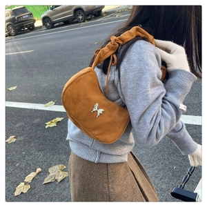 Detail of tan suede underarm bag with silver butterfly buckle and scrunchie strap
