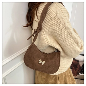 Detail of a brown crescent shoulder bag featuring a golden butterfly metal buckle and suede finish