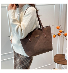 Detail of dark brown suede tote bag featuring metallic rivets and slim leather handles