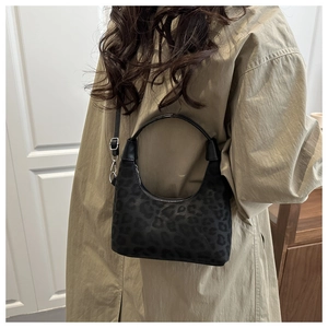 Détail du sac à main en daim à imprimé léopard porté par un mannequin en intérieur