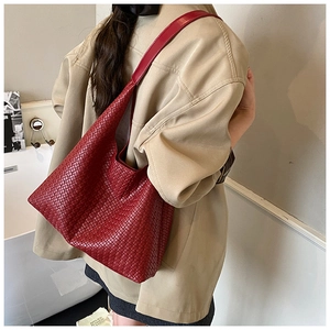 Detail of the deep red woven leather tote bag featuring a textured checkered pattern