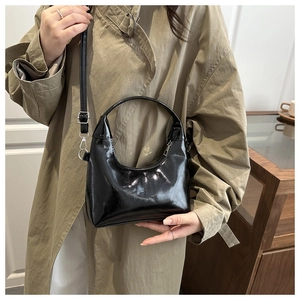 Détail d'un sac cabas en similicuir noir brillant avec poignées rondes et bandoulière