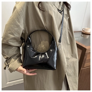 Détails d'un sac à main demi-lune en cuir verni noir brillant avec boucles argentées